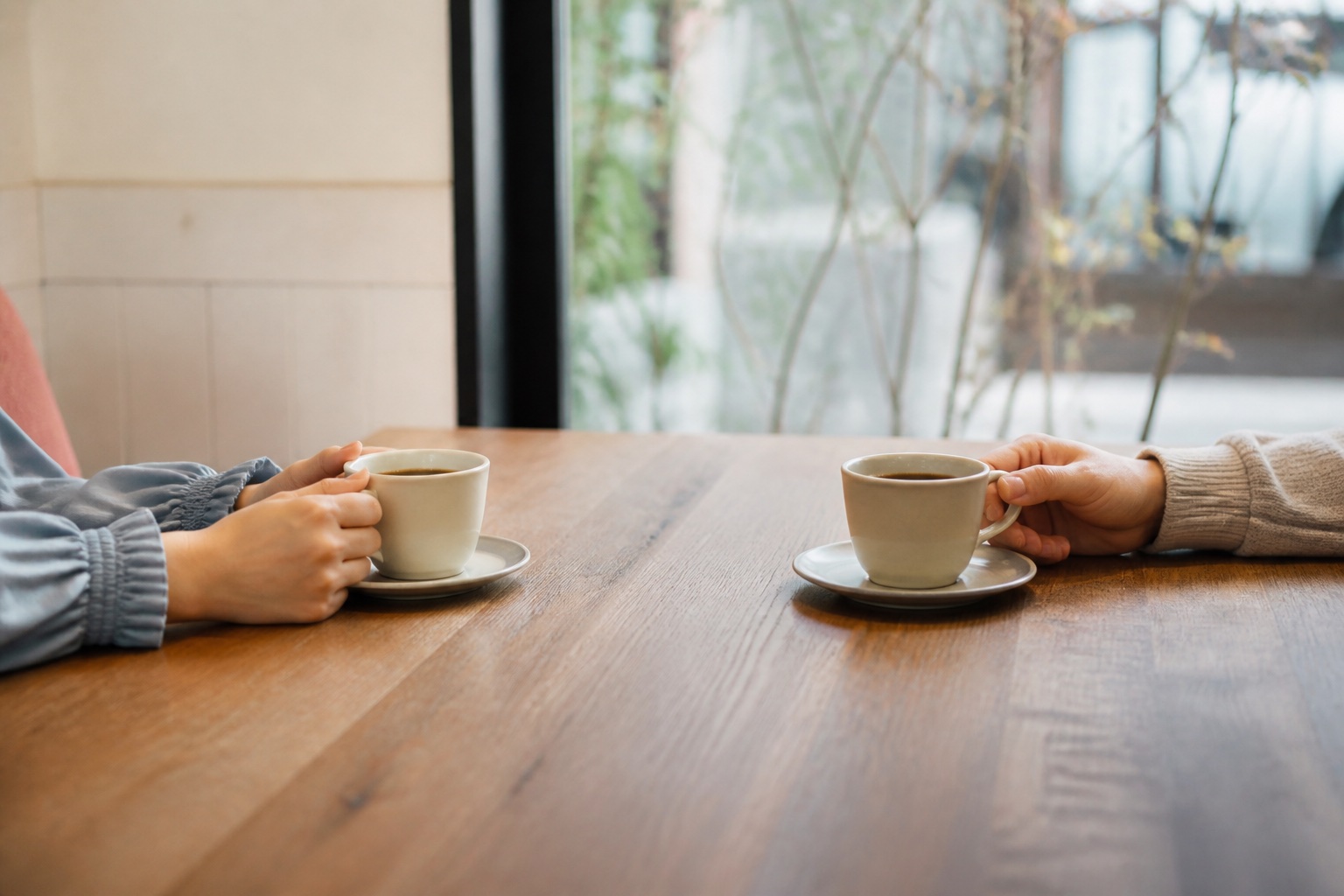 東京のカフェで向かい合う二人のコーヒーカップと手元